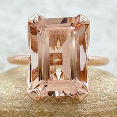 an orange and white diamond ring sitting on top of a rock