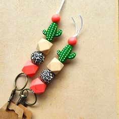 three wooden beads with green, red and white designs are hanging from a keychain