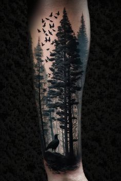 a man's arm with a black and grey tattoo on it, depicting a forest scene