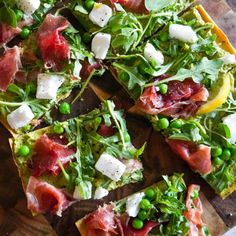 a pizza topped with meat and veggies on top of a wooden cutting board