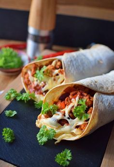 two burritos are sitting on a cutting board