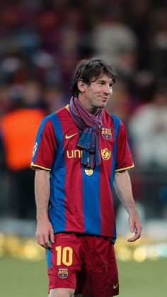 a man standing on top of a soccer field wearing a red and blue uniform with a scarf around his neck