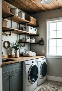 a washer and dryer in a small room with shelves on the wall above them