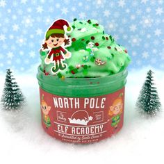 a cupcake with green frosting and an elf figure on top in the snow