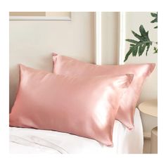 two pink pillows sitting on top of a white bed