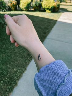 a person's arm with a small crescent tattoo on the left side of their wrist