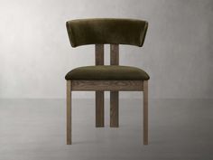 a wooden chair with a green upholstered seat and backrest, in front of a gray wall