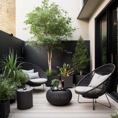 an outdoor living area with black and white furniture, potted plants, and trees