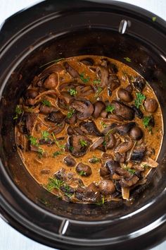 a crock pot filled with mushrooms and sauce