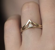 a woman's hand wearing a gold ring with a diamond in the shape of a triangle