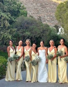 a group of women standing next to each other in front of some trees and bushes