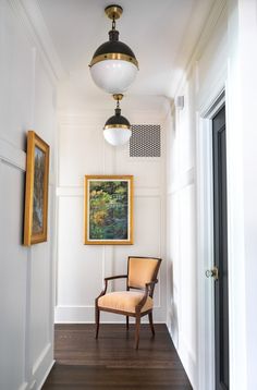 an empty hallway with a chair and painting on the wall