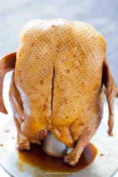 a whole chicken sitting on top of a pan covered in sauce