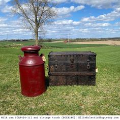 an old trunk sitting in the grass next to a large red container on top of it