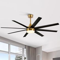 a ceiling fan with four black blades in a living room next to a large window