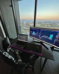 a computer desk with two monitors and a keyboard on it in front of a large window