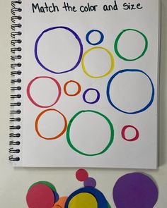 a spiral notebook with different colored circles on it and the words match the color and size