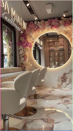 a salon with white chairs and flowers on the wall