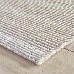 a close up view of a white rug on a wooden floor with wood grains