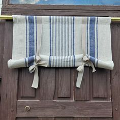 a blue and white striped towel hanging on a wooden door with a window in the background