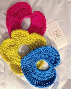 three crocheted donuts sitting on top of a white bed next to a tag