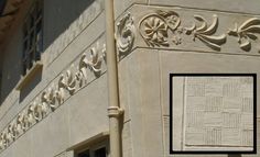 the corner of a building with an ornamental design on it's side and a square window