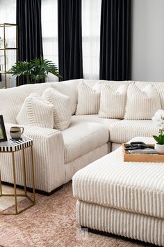 a living room with white furniture and black curtains