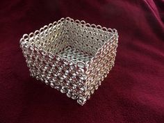 a silver square object sitting on top of a red blanket