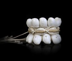 A handwoven white braided rope wide bracelet, decorated with two bands of white curled Shells, a band of cream Cowrie Shells, and a central band of golden round beads. The inner diameter of the bracelet is 2 inches, and the bracelet is 2.1 inches in width. The bracelet is attached by two groups of two, 7.5 inches white cord strands (for adjustable sizing), each decorated at the end with a silver round bead. ► Find these in more dazzling colors here: https://www.etsy.com/listing/231043688/gray-se Handmade Bohemian Braided Bracelets With Shell, Handmade Bohemian Shell Braided Bracelets, Bohemian Handmade Shell Braided Bracelets, White Cowrie Shell Bracelet, White Shell Friendship Bracelets For Vacation, White Shell Bracelet For Vacation, White Cowrie Shell Beaded Bracelet For Beach, White Cowrie Shell Bracelets For Beach, Woven Bracelet Jewelry For Beach