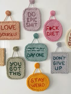 nine crocheted purses hanging from hooks with words written on them and saying don't give up