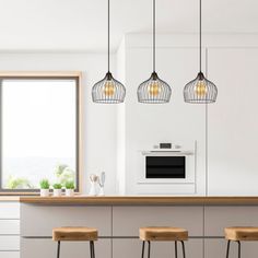 three lights hanging over a kitchen island with stools