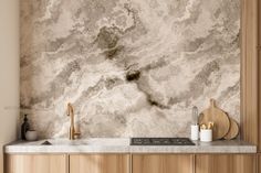 a kitchen with marble counter tops and wooden cabinetry, along with gold faucets