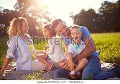 a group of people sitting on top of a blanket in the grass with a butterfly flying over them