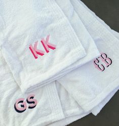 three white towels with pink letters on them