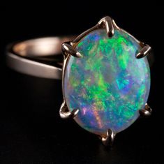 an opal ring is shown on a black surface