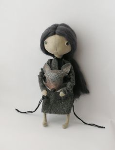 a doll holding a small stuffed animal in its arms and wearing a coat on it's back