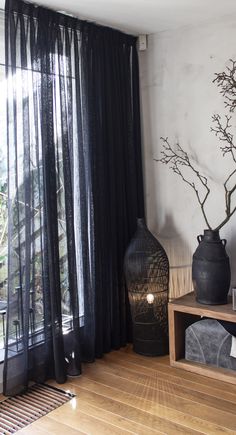 there is a black vase next to a window with sheer curtains on the windowsill