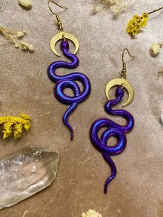 These snake earrings change from deep purple/blue to magenta depending how the light hits them as they sway. Earrings are made of resin Lightweight and durable Assembled using raw brass findings Hooks are gold-plated and nickel-free Dimensions Length: 2.8in/7cm Width: 1in/2.5cm Snake Accessories, Snake Earrings, Fine Art Gallery, Raw Brass, New Tattoos, Deep Purple, Twinkle Twinkle, Statement Earrings, Blue And Purple