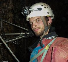 a man wearing a helmet and climbing gear in the dark with his headlamps on