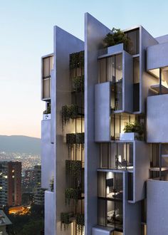 a tall building with many windows and plants on the balconies in front of it