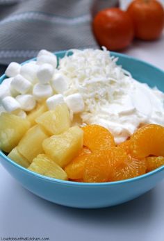 a blue bowl filled with fruit and marshmallows