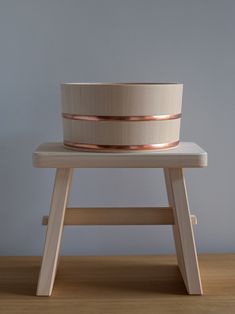 a large wooden bowl sitting on top of a table next to a stool with two legs