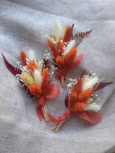 three orange and white flowers on a gray cloth