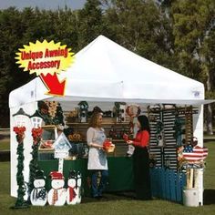 two women standing under a tent selling items