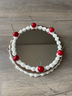 a cake decorated with cherries on top of a wooden table next to a mirror