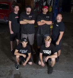 a group of men standing next to each other in front of a red truck at night