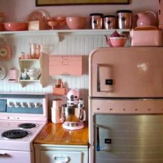 a pink stove top oven sitting inside of a kitchen next to a refrigerator freezer