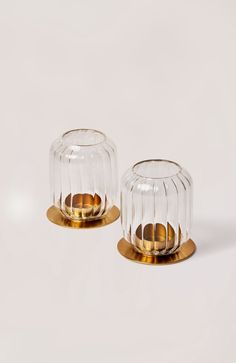 two clear glass candlesticks sitting on top of each other in front of a white background