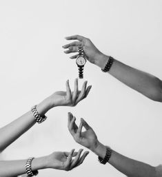 several hands reaching up to each other with wristwatches on their wrists and bracelets around them