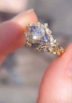 a close up of a person's hand holding a ring with a blue and white stone